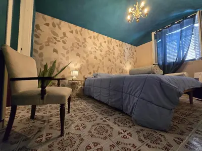 a bedroom with a bed and a chair and a chandelier at CasaRò (delizioso alloggio a Mondello) in Palermo
