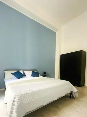 a bedroom with a large white bed with blue pillows at Casa Politeama Florio - Palermo centro in Palermo