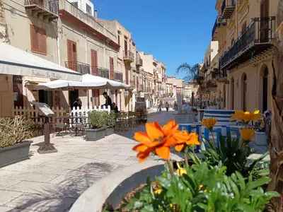 a street with some flowers and tables and buildings at La Casetta di Nino in Castellammare del Golfo