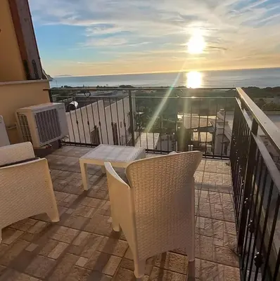 a balcony with a table and chairs and the sunset at Alykè Appartamenti Vacanze Macari in Macari