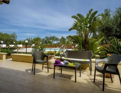 a patio with chairs and a bench and a table at Villa Donna Franca con piscina privata in Castellammare del Golfo