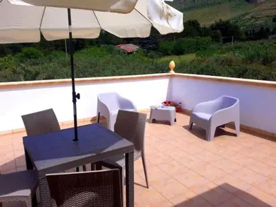 a patio with a table and chairs and an umbrella at Villa Donna Franca con piscina privata in Castellammare del Golfo