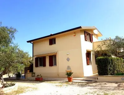 a white house with a potted plant in front of it at Villa Donna Franca con piscina privata in Castellammare del Golfo