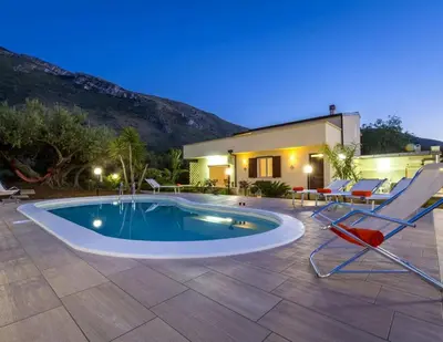 a swimming pool with two chairs and a house at Villa Donna Franca con piscina privata in Castellammare del Golfo