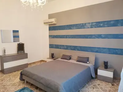 a bedroom with a bed with a blue and white wall at La Vie Est Belle in Balestrate