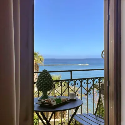a table on a balcony with a view of the ocean at Castellano suites in Castellammare del Golfo