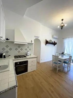 a kitchen with a stove and a dining room with a table at Castellano suites in Castellammare del Golfo