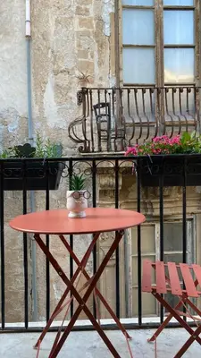 a red table and two chairs on a balcony at GRETA'S APARTMENT DISCESA DELLE CAPRE in Palermo