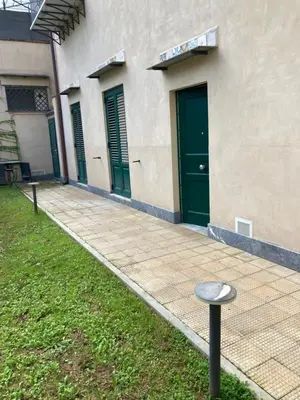a building with green doors and a pole in the grass at studio 338 in Palermo