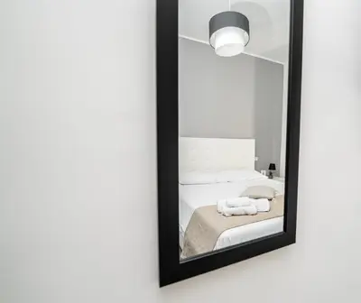 a mirror hanging on a wall with a bed at Modern House Orleans in Palermo