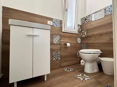 a bathroom with a toilet and a wooden wall at M'AMA apartment 2 in Ficarazzi