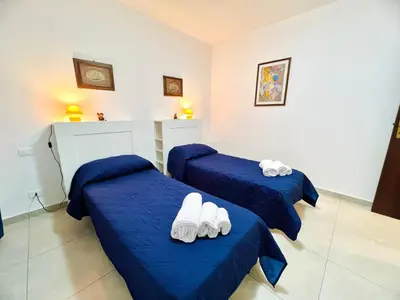 two beds in a room with blue sheets and white towels at L'Angolo del Saraceno in Carini