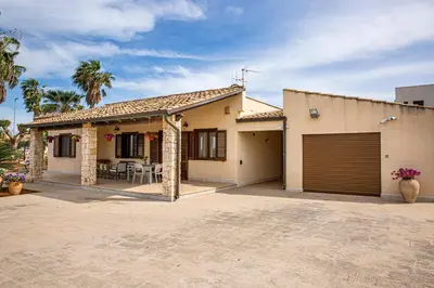 a house with a garage and a patio at Exclusive Palm House near the beach in Alcamo