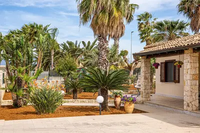 a courtyard with palm trees and a house at Exclusive Palm House near the beach in Alcamo
