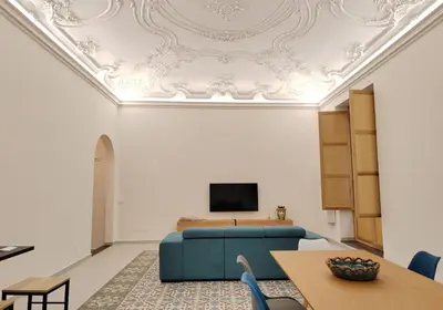 a living room with a blue couch and a tv on a ceiling at Ciuririvù in Palermo