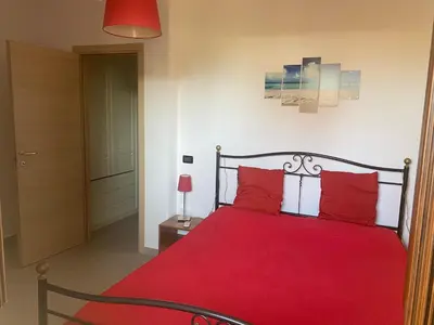 a red bed with red pillows in a bedroom at Casa al mare in Lascari