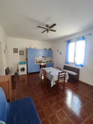 a living room with a table and a ceiling fan at Balestrate holiday home 70 Mq in Balestrate