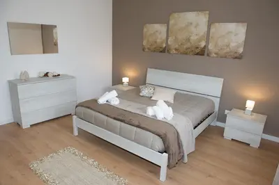 a bedroom with a bed with two night stands and a mirror at Casa Vacanze Ines in Carini