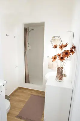 a bathroom with a toilet and a vase of flowers on a counter at Casa Vacanze Ines in Carini