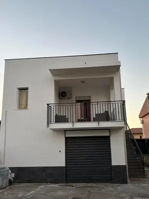 a white building with a garage door and a balcony at Casa Vacanze Ines in Carini