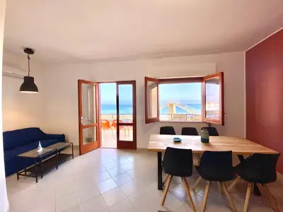 a living room with a table and chairs and the ocean at Brezza Marina Apartment, 50 mt dalla spiaggia in Alcamo