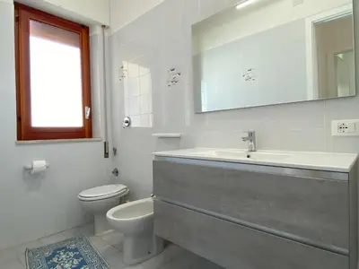 a white bathroom with a sink and a toilet at Brezza Marina Apartment, 50 mt dalla spiaggia in Alcamo
