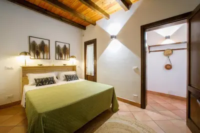 a bedroom with a bed with a green bedspread at Baglio Sammartano ROOM&TOUR in Castelluzzo