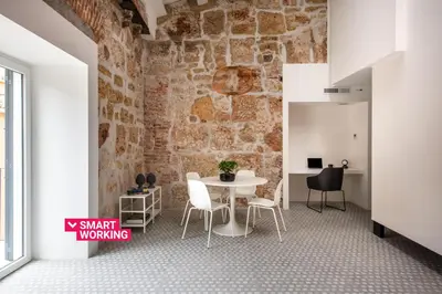 a room with a table and chairs and a brick wall at Casa Design tra le Mura by Wonderful Italy in Palermo
