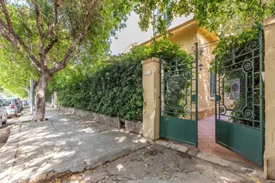 a gate to a house with a tree and a sidewalk at Villa Ammirata Mondello by Wonderful Italy in Mondello