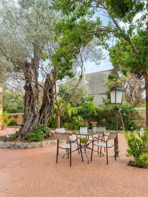 a table and chairs in a park with a tree at Villa Ammirata Mondello by Wonderful Italy in Mondello