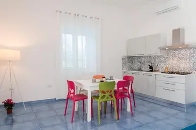 a kitchen with red and green chairs and a table at GuestHost - La Giara - Villa with Swimming Pool and Parking in Castellammare del Golfo