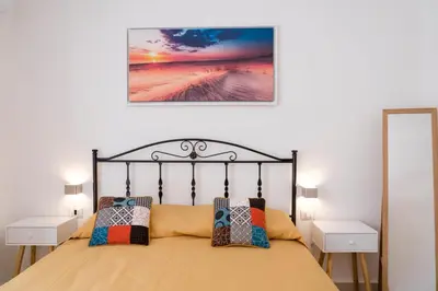 a bedroom with a bed and two white tables and a picture at GuestHost - La Giara - Villa with Swimming Pool and Parking in Castellammare del Golfo