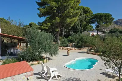 a swimming pool in a garden with two chairs and a table at GuestHost - La Giara - Villa with Swimming Pool and Parking in Castellammare del Golfo