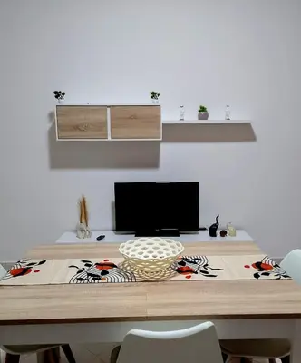 a dining room table with chairs and a television at Appartamento Matteo in Trappeto