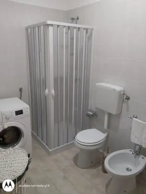 a bathroom with a toilet and a washing machine at Appartamento Matteo in Trappeto