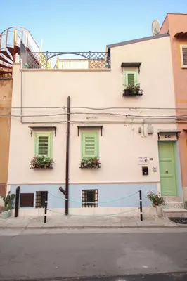 a building with green doors and windows on a street at Donna Carmela in Porticello