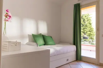a room with a bed with green pillows and a window at Isola Suite in Isola delle Femmine