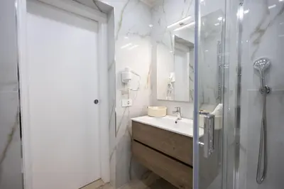 a white bathroom with a shower and a sink at Mangano Suites in Palermo