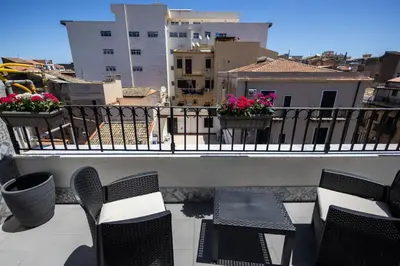 a balcony with chairs and tables and flowers on a building at Mangano Suites in Palermo