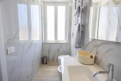 a bathroom with a sink and a toilet and a window at Mangano Suites in Palermo