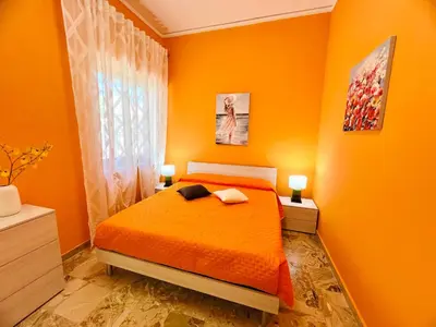 a orange bedroom with a bed and a window at Orange House in Isola delle Femmine