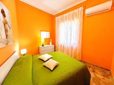 a green bed in a room with orange walls at Orange House in Isola delle Femmine
