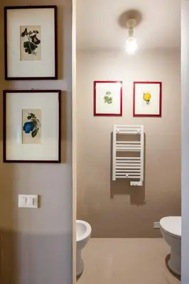 a bathroom with a toilet and pictures on the wall at Palazzo Sant'Isidoro by DomuSicily in Palermo