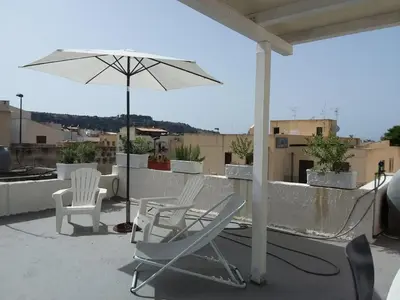 a patio with chairs and an umbrella on a roof at Casa Finuzza in San Vito lo Capo