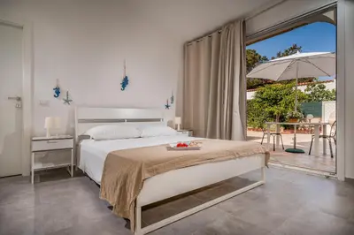 a bedroom with a bed and a patio with an umbrella at Villa Spada con ampi spazi esterni in San Vito lo Capo