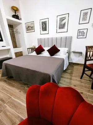 a bedroom with a bed and a red chair at Domus Vetriera in Palermo