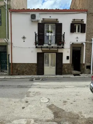 a white building with a balcony on a street at House of joy in Corleone