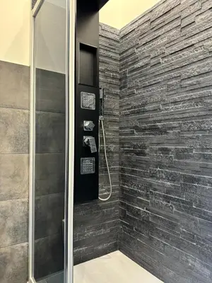a bathroom with a shower with a stone wall at House of joy in Corleone