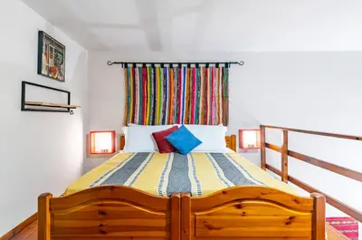 a bedroom with a wooden bed with colorful pillows at GuestHost - The Traveller's House - Palermo Station Apartments in Palermo