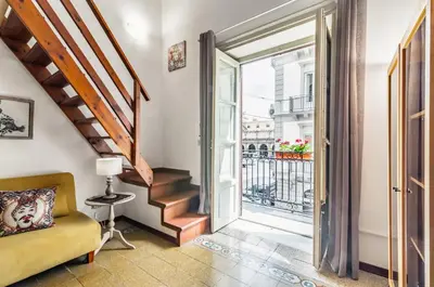 a living room with a yellow couch and a sliding glass door at GuestHost - The Traveller's House - Palermo Station Apartments in Palermo